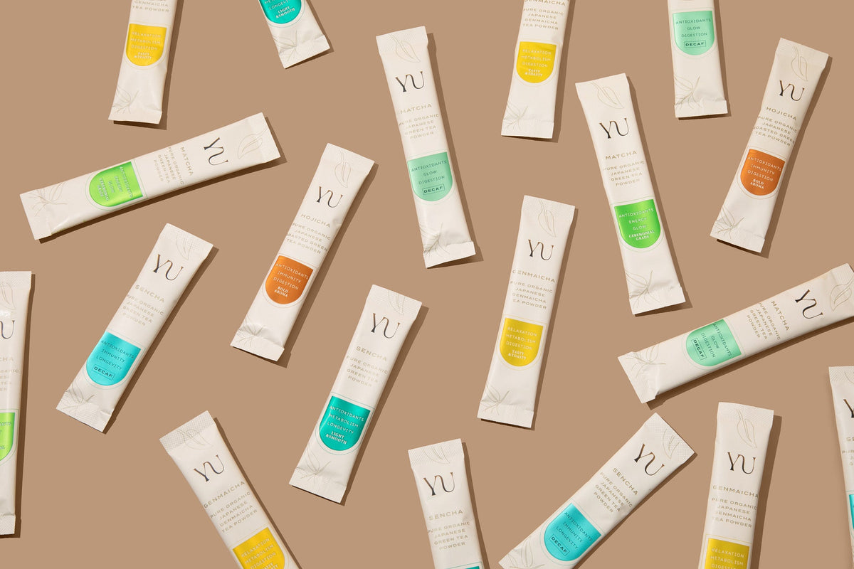Yu Tea single-serving sticks of all six teas scattered on a warm tan background